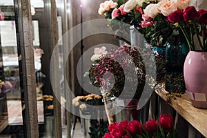 Many different fresh colors in vases on shelves in a flower shop in refrigerators.