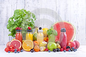 Many different fruits and berries and juices in plastic bottles. Watermelon, banana, applcsin, blueberries, strawberries, basil on