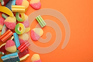 Many different jelly candies on orange background, flat lay. Space for text