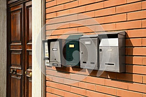 Many different mailboxes on red brick wall of building