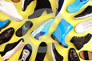 Many different pairs of shoes for different seasons. a lot of shoes on yellow background, top view.