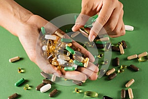 Many different pills for treatment and recovery health on green background. Set of omega and zinc pills, antioxidants