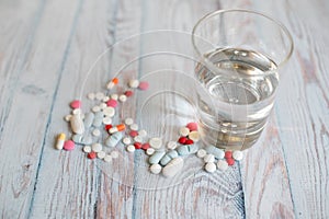 Many different pills water glass on blue wooden background