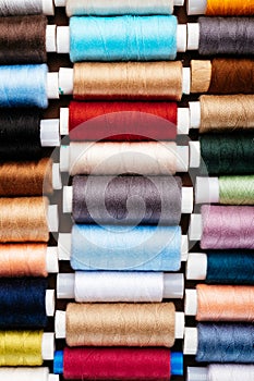 Many different reels with threads, flat lay, top view. Colored threads, close-up, bright background. Cutting and sewing clothes