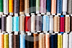 Many different reels with threads, flat lay, top view. Colored threads, close-up, bright background. Cutting and sewing clothes