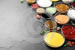 Many different sauces on black table, space for text