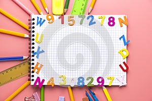Many different school supplies and empty notepad white sheet of paper on pink copy space background. Back to school concept