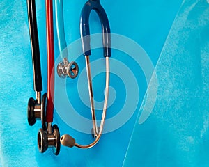 Many of different sizes and colors stethoscopes hanging over discardable medical gound.