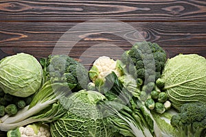 Many different types of fresh cabbage on wooden table, flat lay. Space for text