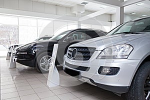 Many different used cars are in the dealership of a dealer accepted by the trade-in system during a sale in a bright room with