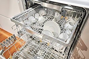 Many of dirty dishes in the dishwasher. Built-in dishwashers with opened door. Home appliance dishwasher machine in