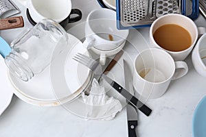 Many dirty utensils and dishware on countertop in messy kitchen, above view