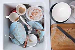 Many dirty utensils and dishware in kitchen sink, top view