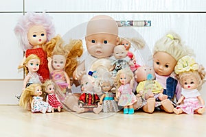 Many dolls sits on floor in nursery, playroom. Lot of toys in children`s room