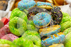 Many donuts with multi-colored glaze on the counter in a store. Delicious baked goods. Close-up