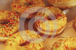 Many donuts with yellow icing on the counter in a store. Traditional mouth-watering sweets. Close-up