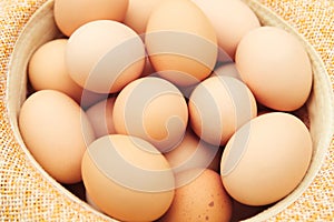 Many eggs. Straw hat. Chicken eggs in wooden basket on green nature floor at cloudy day. Backdrop. Organic food