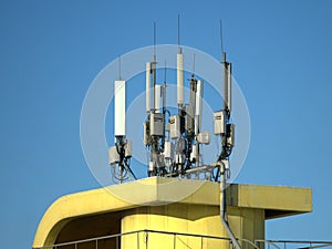 Many electronics aerials on yellow building top