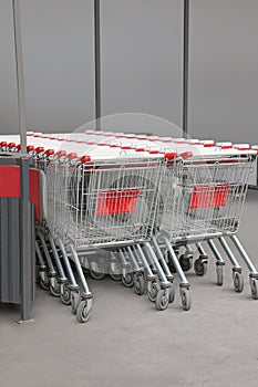 Many empty metal shopping carts near supermarket outdoors