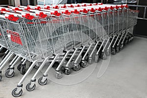 Many empty metal shopping carts near supermarket outdoors