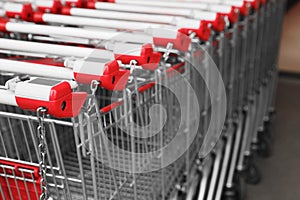 Many empty metal shopping carts near supermarket outdoors, closeup. Space for text