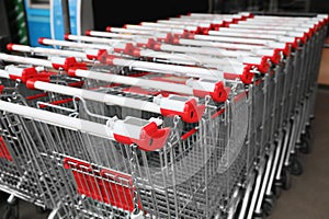 Many empty metal shopping carts near supermarket outdoors