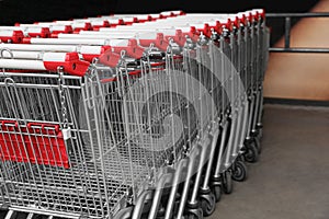 Many empty metal shopping carts near supermarket outdoors, space for text