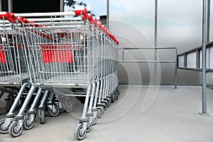 Many empty metal shopping carts near supermarket outdoors, space for text