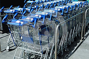 Many empty shopping carts near supermarket, closeup