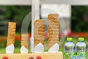 Many empty wafer sweet cornets for ice cream on naturale green blurry background. Selective focus. Copy space. Real