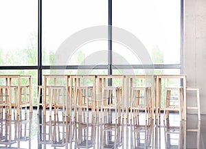 Many empty wooden stools near a table in a corporate lobby area, luch room, calm business canteen, no people, nobody. Vacant seats