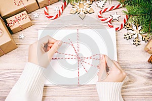 Many envelopes tied with rope. Close-up top view of famale hands with envelope. Pine cones and christmas decoration on old wooden