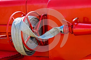Fire truck with firehose. Side view of red municipal fire engine standing idle