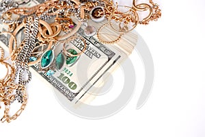 Many expensive golden and silver jewerly rings, earrings and necklaces with big amount of US dollar bills on white background.