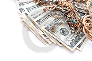 Many expensive golden and silver jewerly rings, earrings and necklaces with big amount of US dollar bills on white background.