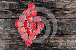 Many extinguished red candles in diamond shape on wooden table