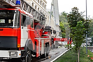 Many fire engine trucks with ladder and safety equipment at accident in highrise tower residential apartment or office