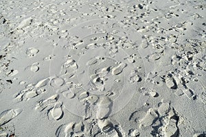 Many foot prints on a white beach sand