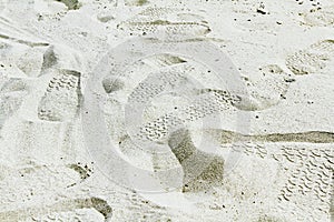 Many footprints on the white sand or beach.