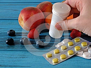 Many fresh natural fruits vs pills. Natural vitamin in fruits vs synthetic vitamin in pills. Choice between natural and synthetic