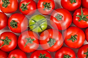 Many fresh red tomatoes, one green, background top view