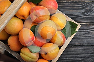 Many fresh ripe apricots in wooden basket on table, top view