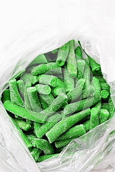 Many frozen bright green beans pods in a package, vertical frame