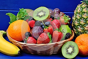 Many fruits in a basket on blue table