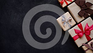 Many gift boxes wrapped in brown paper and tied with different ribbons on a black background, top view, copy space.Christmas and