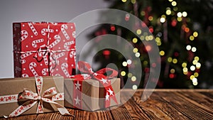 Many gift boxes wrapped in multi-colored paper on a wooden table against the background of a beautiful Christmas tree, copy space