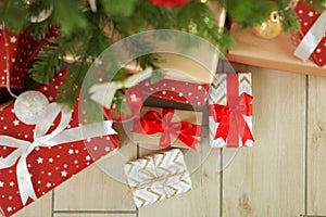 Many gifts under a festively decorated Christmas tree in a bright interior