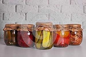 Many glass jars with different preserved vegetables on light grey table