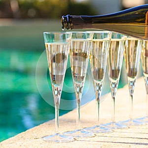 Many glasses of champagne or prosecco near resort pool in a luxury hotel. Pool party.