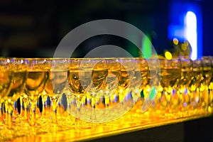 Many glasses with champagne or white wine in a row in a bar. Alcohol background